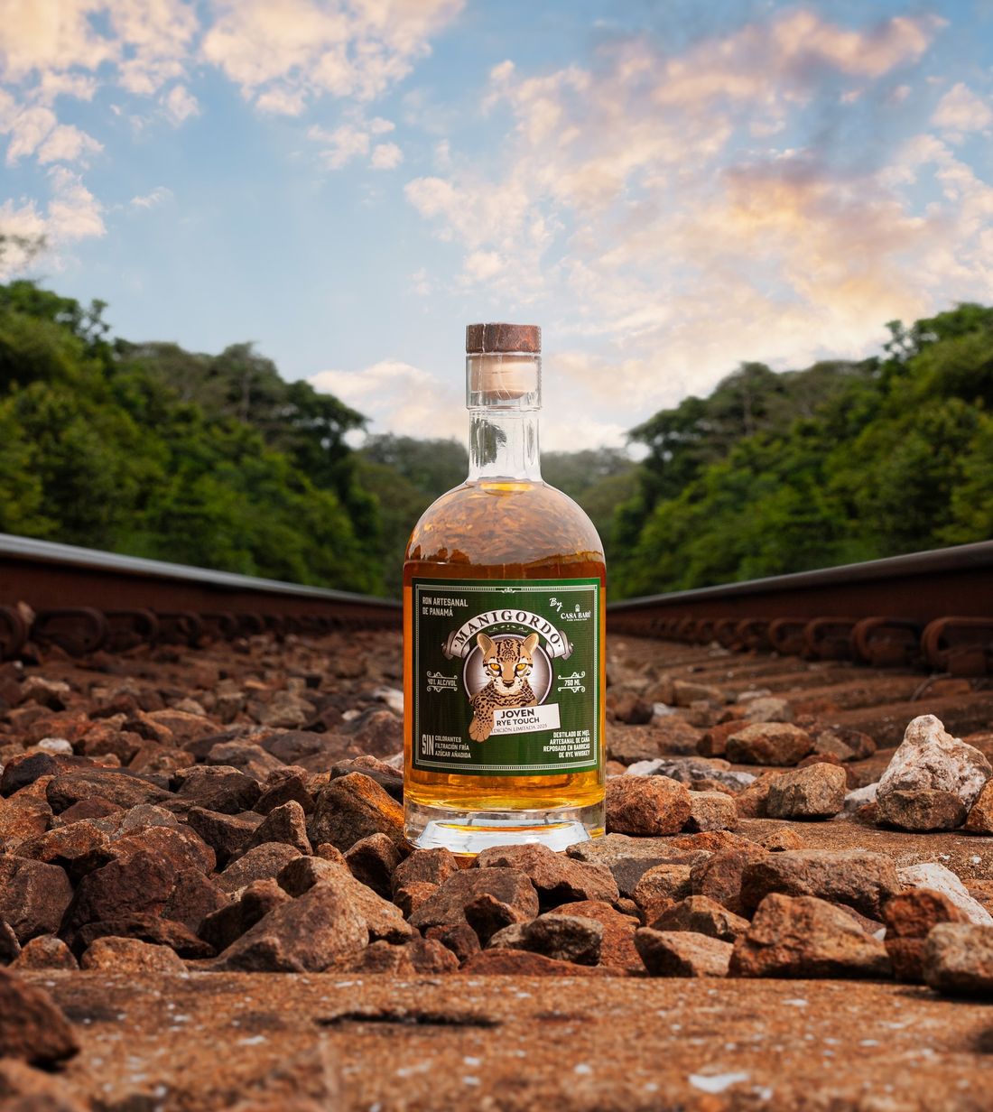 Botella de Manigordo Rye Touch de Casa Barú sobre las piedras de la vía del tren