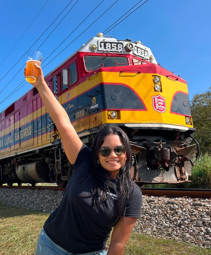 Una chica de Manigordo levanta una pinta frente a la locomotora del Panama Canal Railway