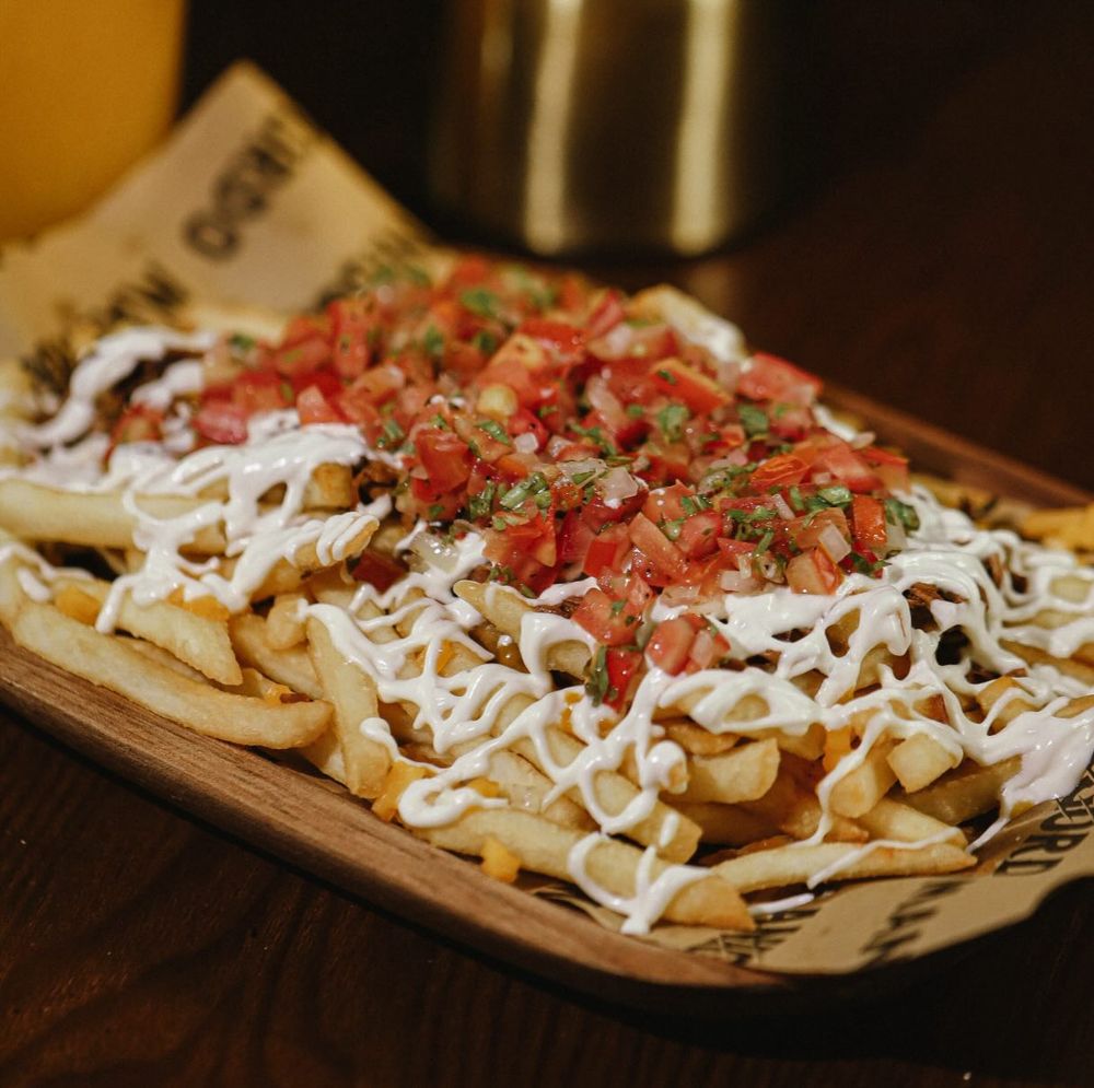 Papas salvajes con ropa vieja ahumada, sour cream y pico de gallo